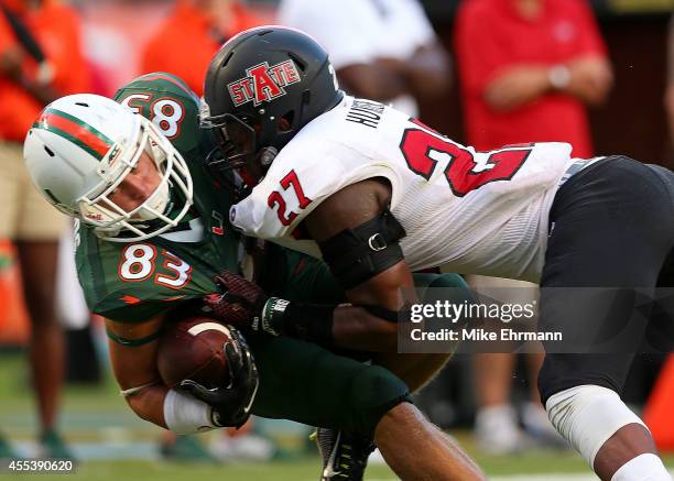 Braxton Berrios of the Miami Hurricanes is tackled after a catch by Money Hunter of the Arkansas State Red Wolves during a game at Sunlife Stadium on...