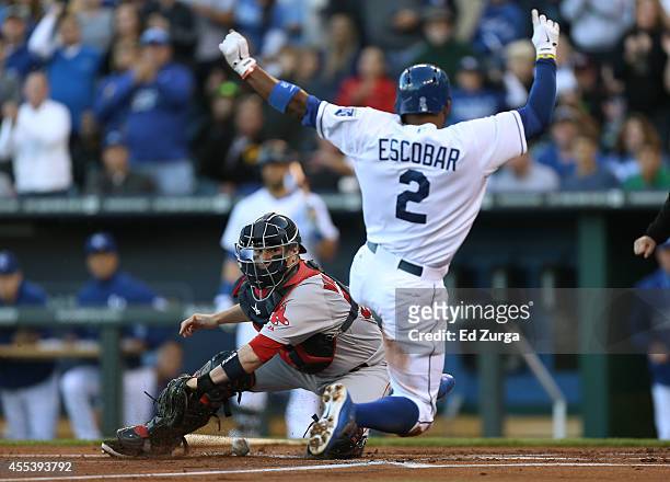 Alcides Escobar of the Kansas City Royals slides into home to score past Christian Vazquez of the Boston Red Sox on a Norichika Aoki single in the...