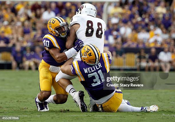 Duke Riley and D.J. Welter of the LSU Tigers bring down Harley Scioneaux of the Louisiana Monroe Warhawks during the first quarter of a game at Tiger...