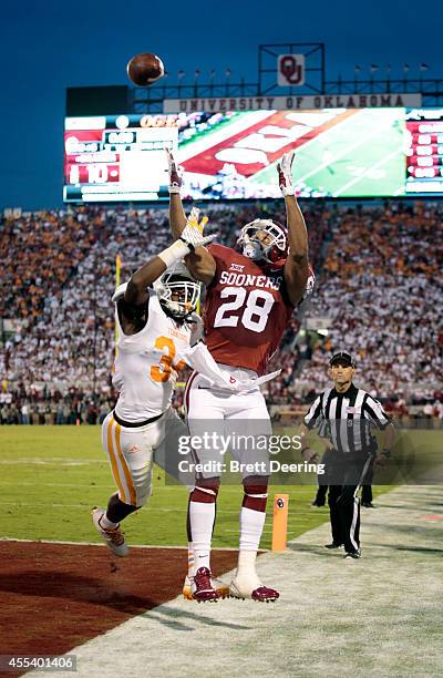 Running back Alex Ross of the Oklahoma Sooners tries to catch a touchdown pass as linebacker Jalen Reeves-Maybin of the Tennessee Volunteers defendes...