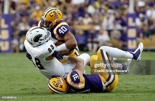 Duke Riley and D.J. Welter of the LSU Tigers bring down Harley Scioneaux of the Louisiana Monroe Warhawks during the first quarter of a game at Tiger...