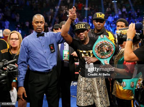 Referee Kenny Bayless holds up Floyd Mayweather Jr.'s hand as he celebrates his unanimous-decision victory over Marcos Maidana during their WBC/WBA...