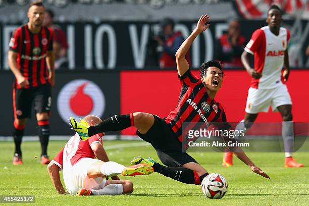 Makoto Hasebe of Frankfurt is challenged by Tobias Werner of Augsburg during the Bundesliga match between Eintracht Frankfurt and FC Augsburg at...