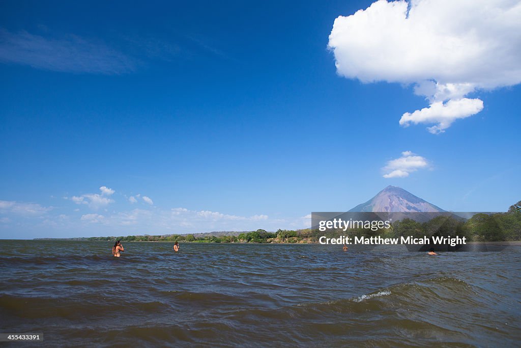 Friends play water frisbee next to a volcano.