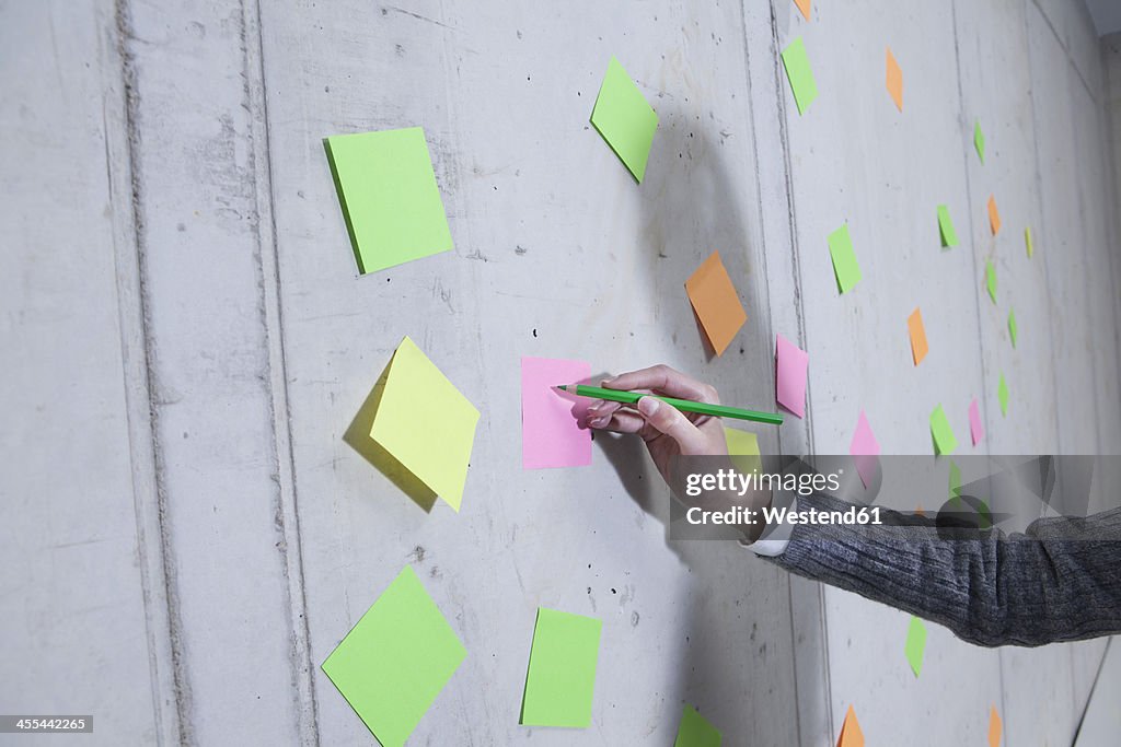 Germany, North Rhine Westphalia, Cologne, Businesswoman writing on adhesive note