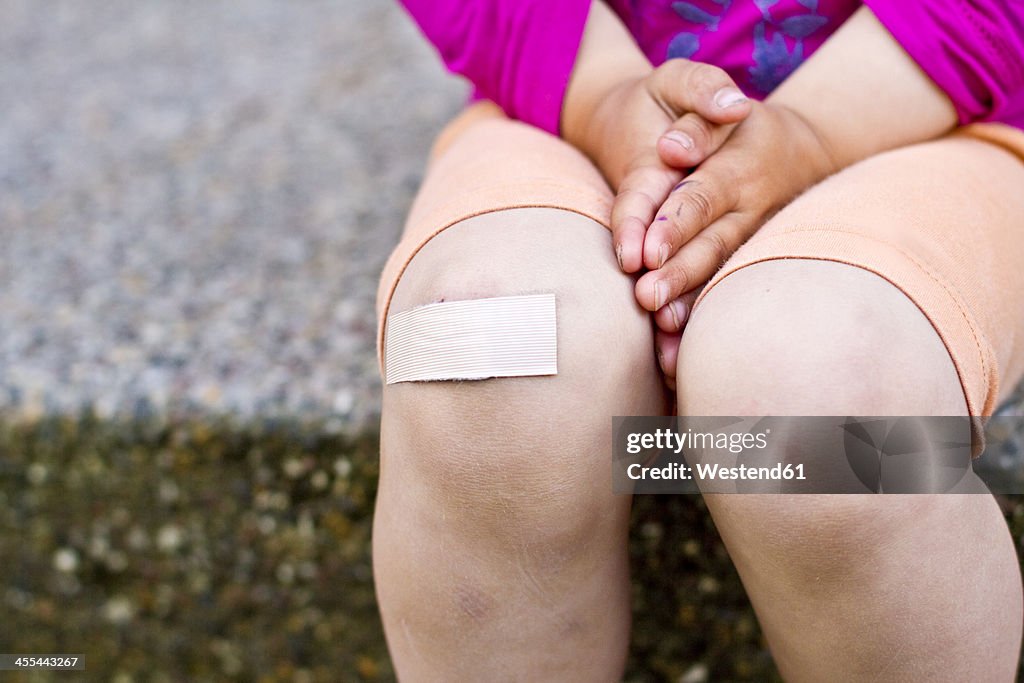 Germany, Kiel, Girl with patch on knee, close up