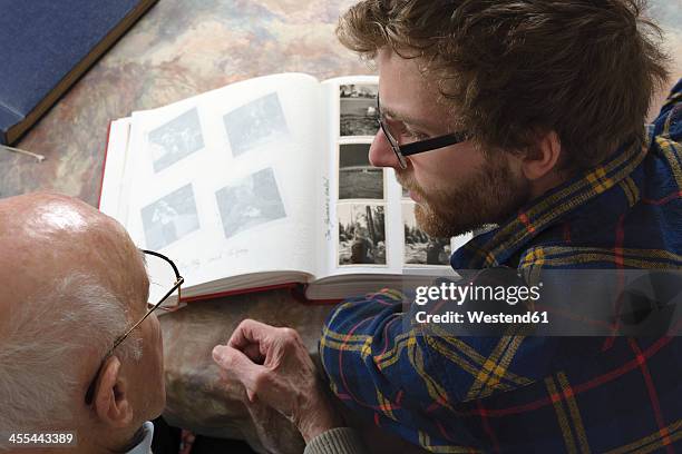 germany, baden wuerttemberg, grandfather and grandson looking photo album, close up - looking at a photo album stock-fotos und bilder