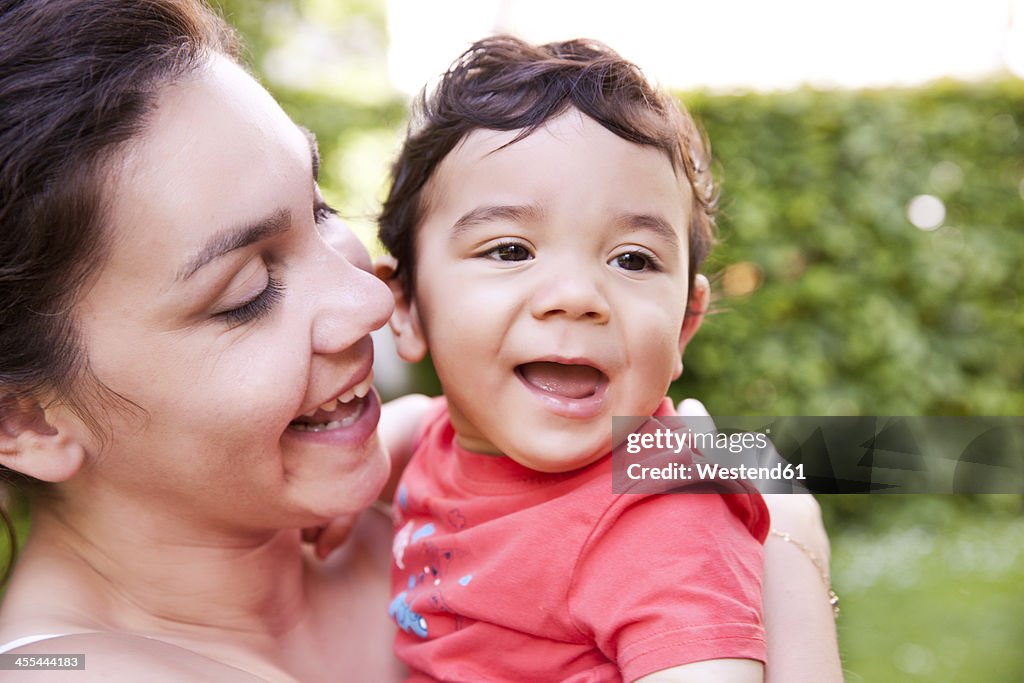 Mother cuddling her baby boy, smiling