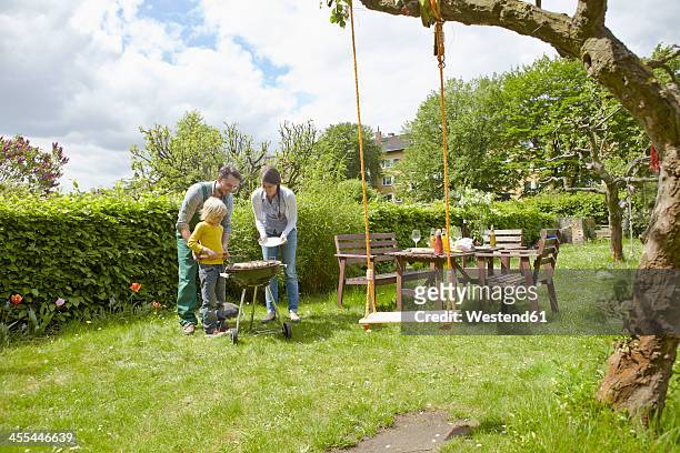 germany, cologne, family having barbecue in garden - jeans latzhose frau stock-fotos und bilder