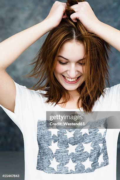 young woman pulling her hair, smiling - hair pulling stock pictures, royalty-free photos & images