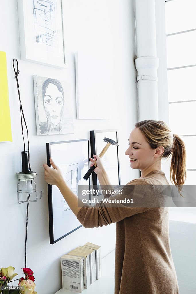 Germany, Bavaria, Munich, Young woman holding picture frame in front of wall