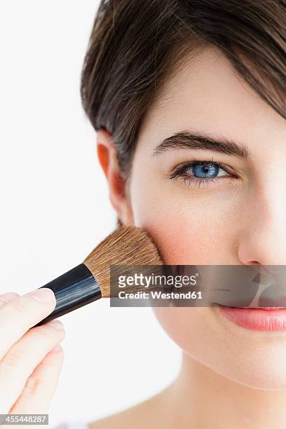 germany, bavaria, munich, young woman using blusher brush, close up - blusher stock-fotos und bilder