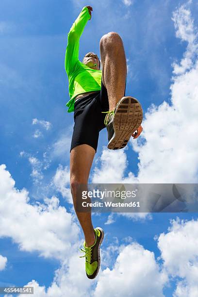 germany, young man doing long jump in track - mens long jump stockfoto's en -beelden