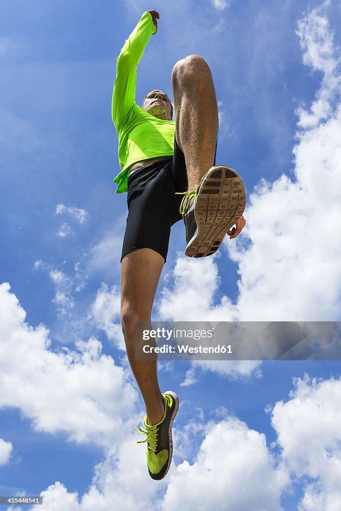 Germany, Young man doing long jump in track