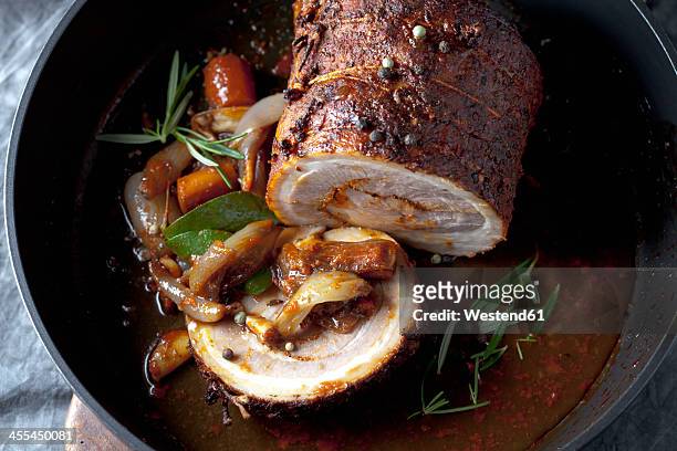 rolled roast pork and braised vegetables in frying pan, close up - schweinebraten stock-fotos und bilder