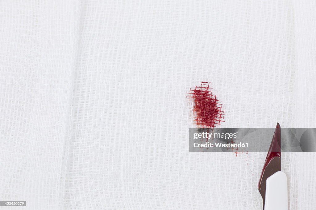 Germany, Freiburg, Surgery swab with scalpel and blood, close up