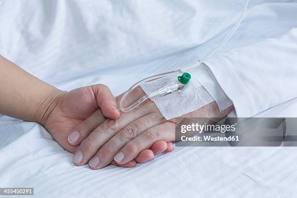 germany, freiburg, woman holding hand of man in hospital, close up - iv drip womans hand fotografías e imágenes de stock