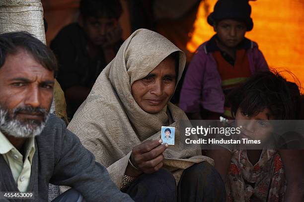 Nawab Ali with his wife Balkeesha show the photograph of their 11-year-old son who died in the camp due to cold just three days after they came to...
