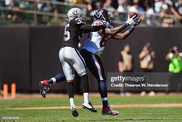 Andre Johnson of the Houston Texans catches a pass for a first down while defended by Chimdi Chekwa of the Oakland Raiders during the first quarter...
