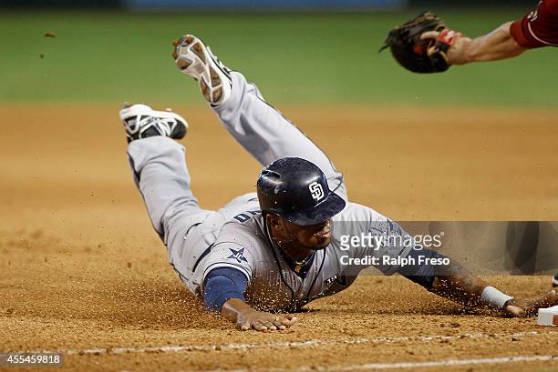 Rymer Liriano of the San Diego Padres dives back to first base to avoid being doubled up on a deep fly ball during the seventh inning of a MLB game...