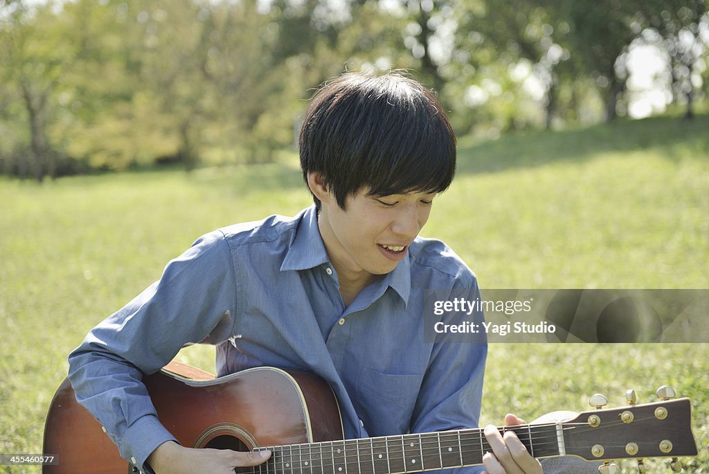 Man playing the guitar in the green