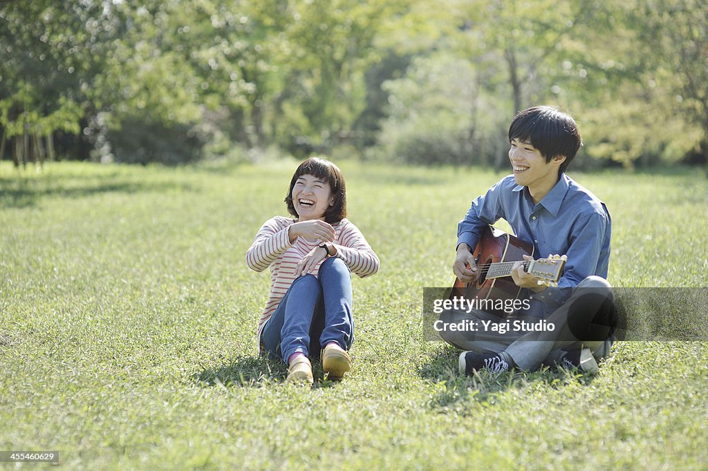 Young couple  playing the guitar in the green