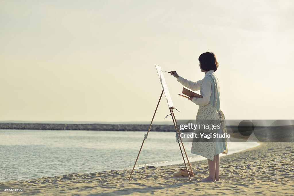 Woman drawing the oil painting on the beach