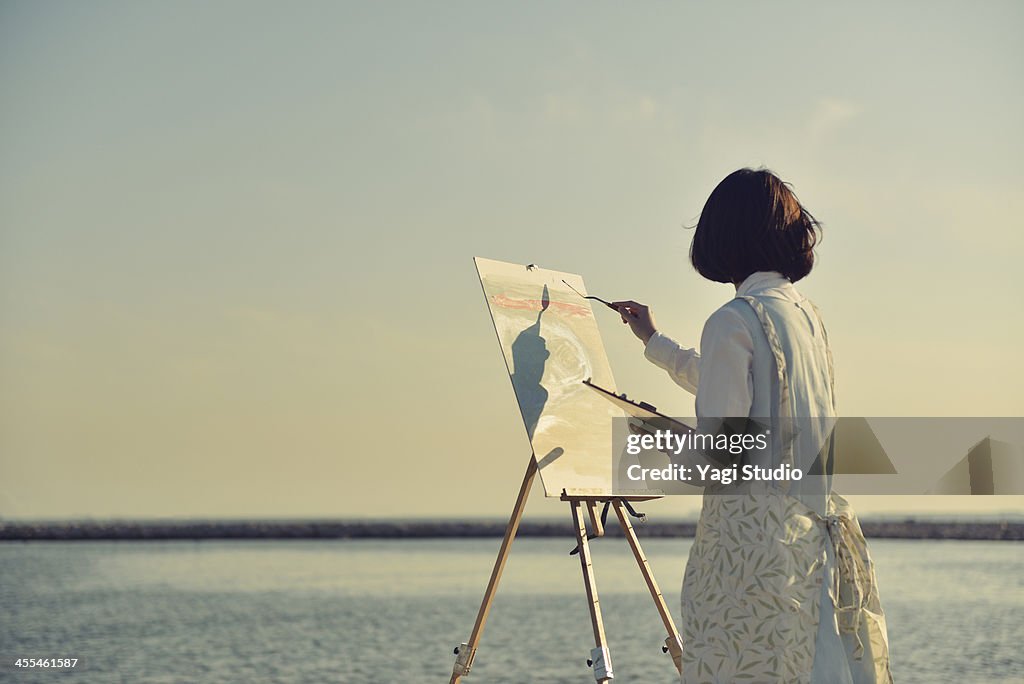 Woman drawing the oil painting on the beach