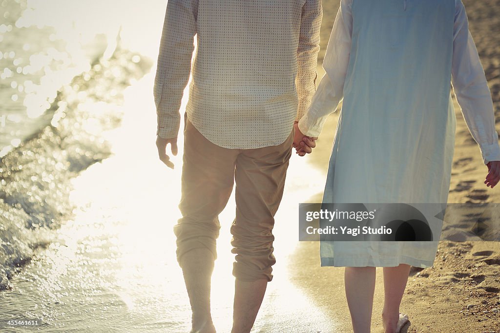 Couple walking along beach holding hands