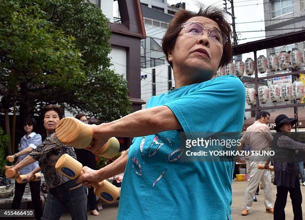 Elderly residents work out with wooden dumb-bells in the grounds of a temple in Tokyo on September 15, 2014 to celebrate Japan's...
