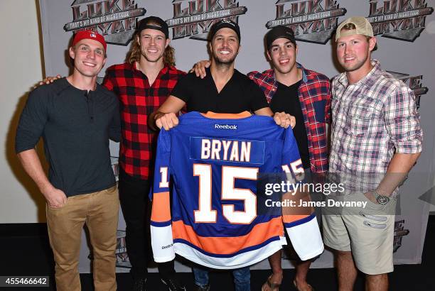 New York Islanders players Casey Cizikas, Matt Martin, Travis Hamonic and Josh Bailey present singer Luke Bryan with a personalized Islanders jersey...