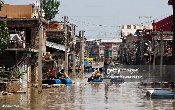 Kashmiri flood victims rows their makeshift rafts past submerged houses in the Bemina area on September 15, 2014 in Srinagar, the summer capital of...