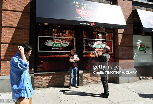 Tourists take photos outside a temporary "pop up" reproduction of the "Central Perk" coffee shop, a center piece set of the television situation...