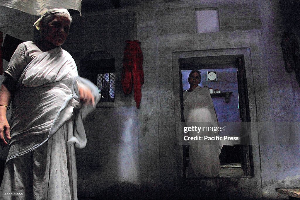 An elderly Indian widow watches as she steps out from her...