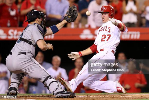 Mike Trout of the Los Angeles Angels of Anaheim slides home ahead of the throw to catcher Mike Zunino of the Seattle Mariners with the third run of...