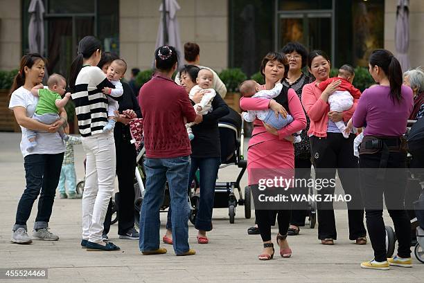 Group of women hold babies gathering at a residential area in Beijing on September 16, 2014. China began to implement the loosening of its...