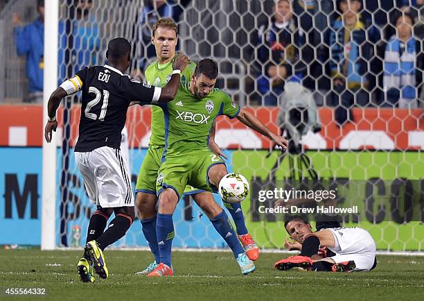 Defender Zach Scott of the Seattle Sounders FC clears the ball away from midfielder Maurice Edu and a fallen forward Sebastien Le Toux of the...