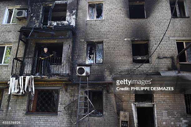 Man cleans up his burnt flat after a building was hit by shelling this morning in the Kievsky district near the international airport on September...
