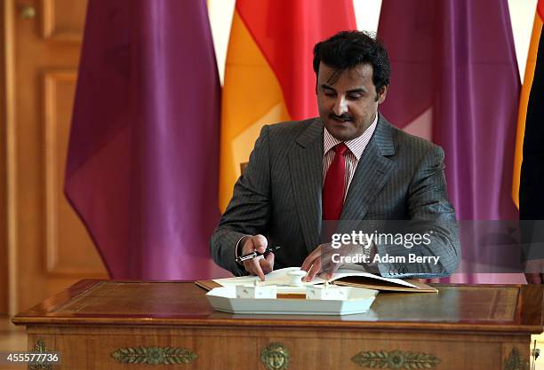 Sheikh Tamim bin Hamad Al Thani, the eighth and current Emir of the State of Qatar, signs the guest book as he meets with German President Joachim...