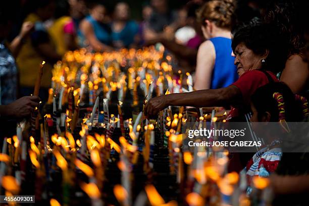 Woman light candles to the Virgin at the Basilica de Guadalupe church in San Salvador, El Salvador on December 12, 2014 during the celebration of the...