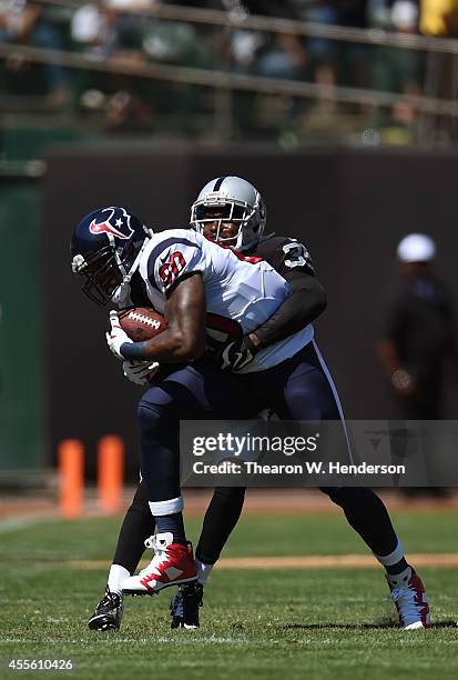 Andre Johnson of the Houston Texans catches a pass for a first down while defended by Chimdi Chekwa of the Oakland Raiders during the first quarter...