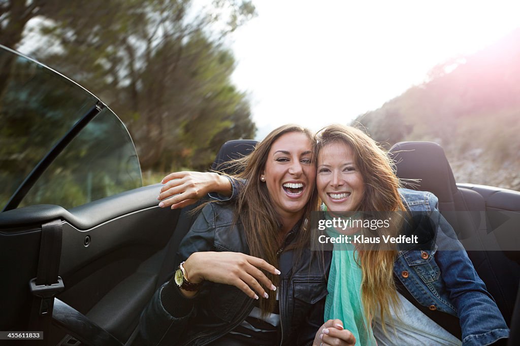 Two friends laughing in the backseat of car