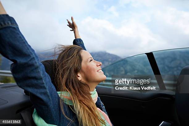 girl smiling with raised arms, riding car - convertible car fotografías e imágenes de stock
