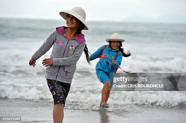 Andean girls run ahead of water ripples as one hundred and forty sixth grade school children, from Andean and Amazonian communities, visit a beach...