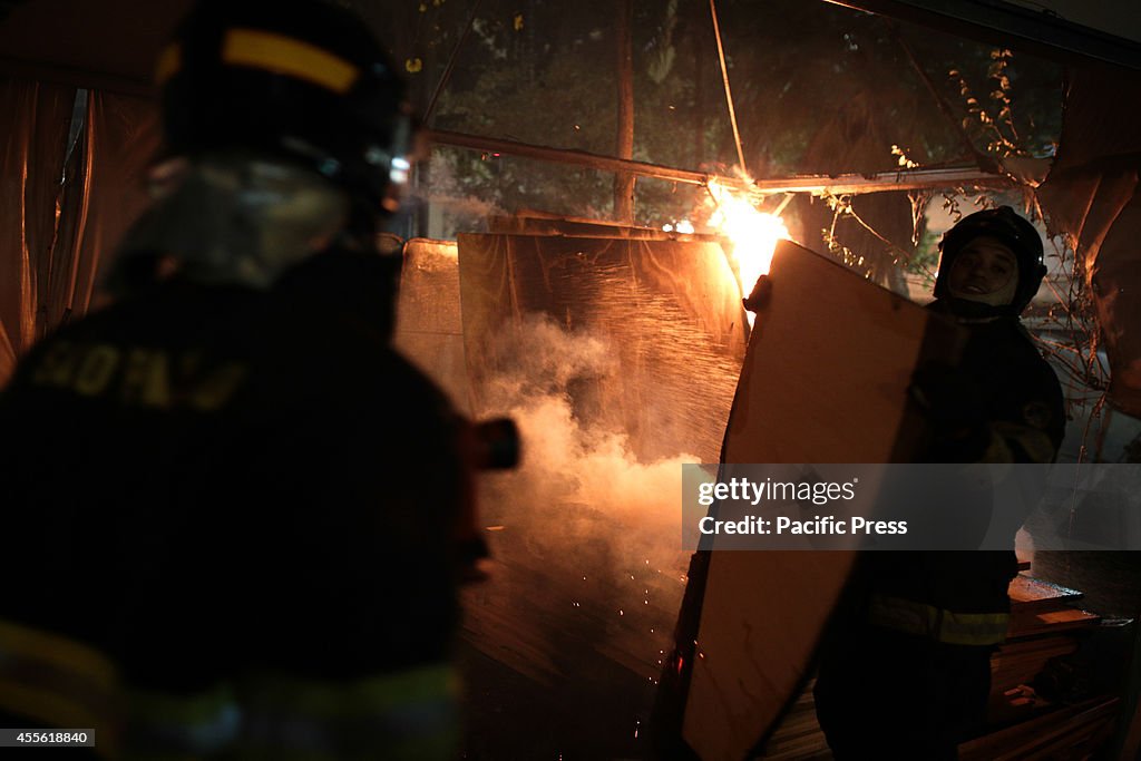 Firefighters try to put out the fire from a tent in the...