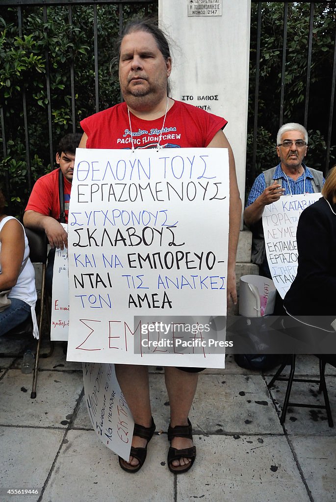 A blind man holds a placard that attacks government politics...