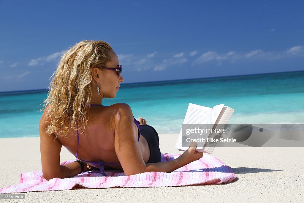 Woman reading book on beach