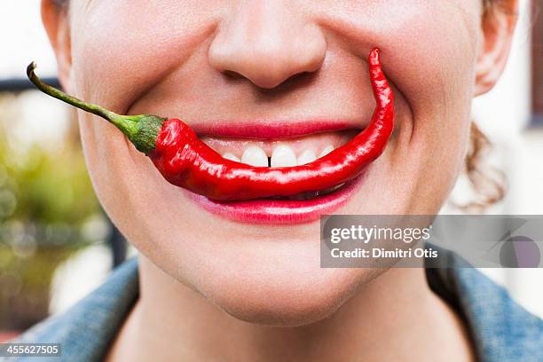 young woman biting into red hot chilli - female eating chili bildbanksfoton och bilder