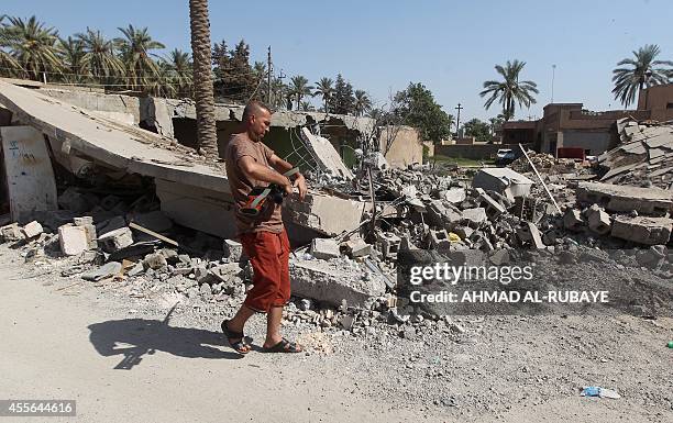 An Iraqi Sunni fighter walks past a destroyed building after government security forces and militia retook the city from Islamic State group...