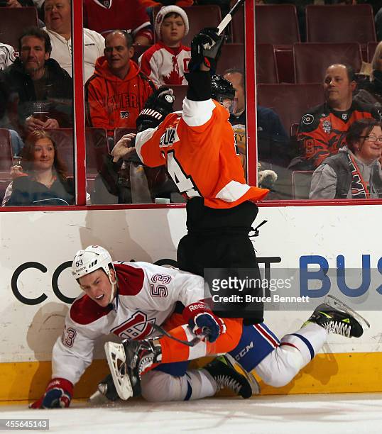 Ryan White of the Montreal Canadiens is hit into the boards by Sean Couturier of the Philadelphia Flyers during the first period at the Wells Fargo...
